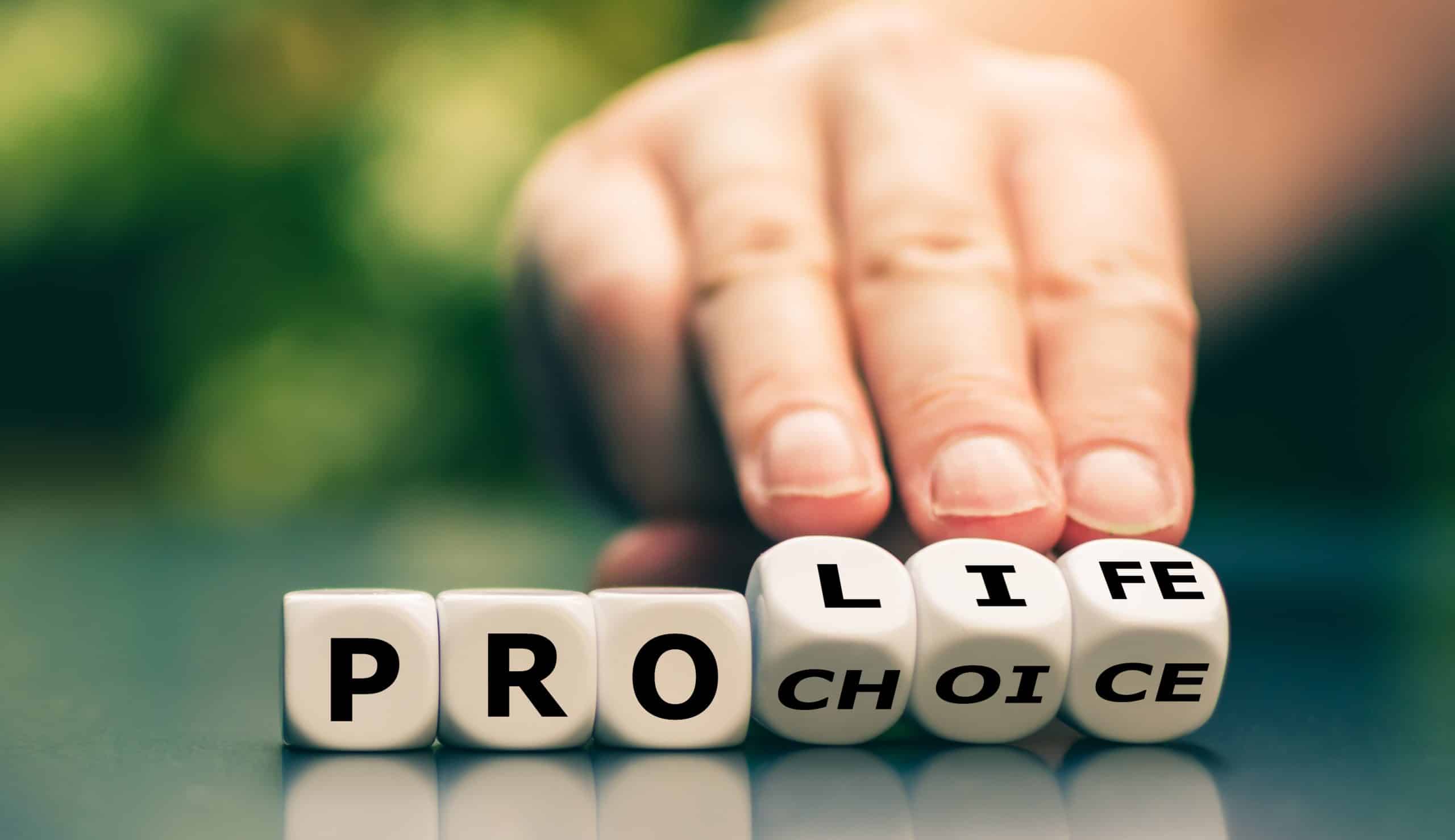 Hand turns dice and changes the expression “pro choice” to “pro life”. pro-life vs pro-choice